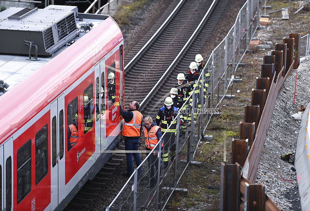 Firefighters go to an S-Bahn together with railway staff at a railway site in Munich, Germany, Wednesday, Dec. 1, 2021. Police in Germany say three people have been injured including seriously in an explosion at a construction site next to a busy railway line in Munich. (Sven Hoppe/dpa via AP)