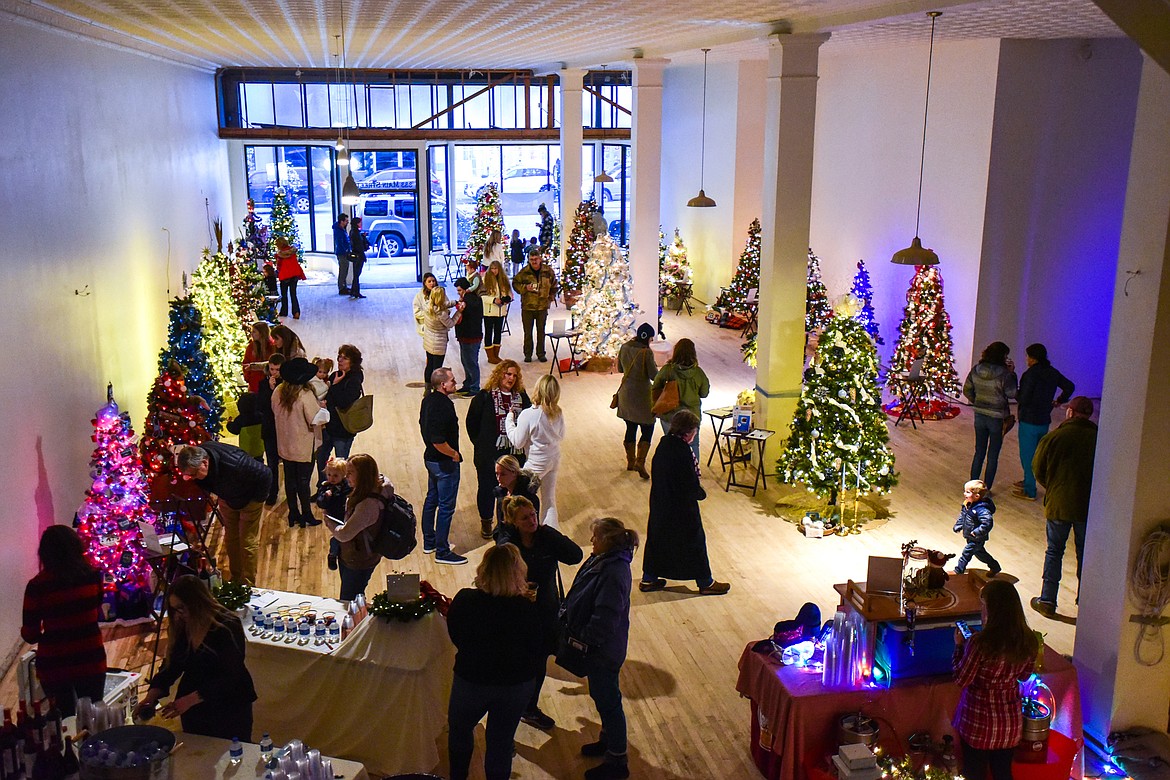 Visitors walk through the Festival of Trees at the former Alpine Lighting building at 333 S. Main St. in Kalispell on Friday, Dec. 3. The Festival involves a silent auction where visitors can bid on Christmas trees decorated by local businesses and community members. Proceeds from the auction benefit the Nate Chute Foundation. (Casey Kreider/Daily Inter Lake)