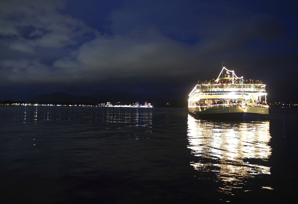 A cruise ship with Journey to the North Pole Cruises from The Coeur d'Alene Resort arrives at the North Pole with the lights of Coeur d'Alene in the background.
