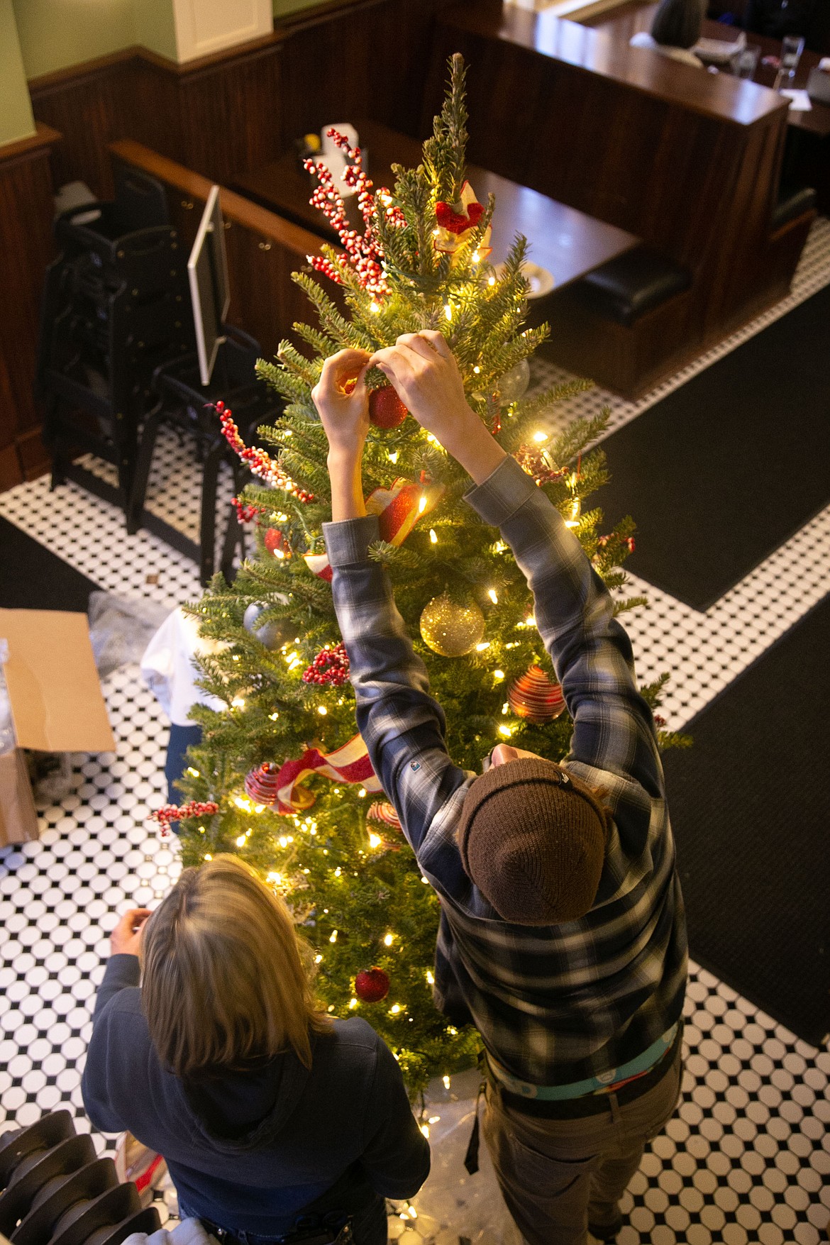 Maddox Kurtz and Kari Palmer decorate a Christmas tree at McDuff's Brewing Company on Friday.