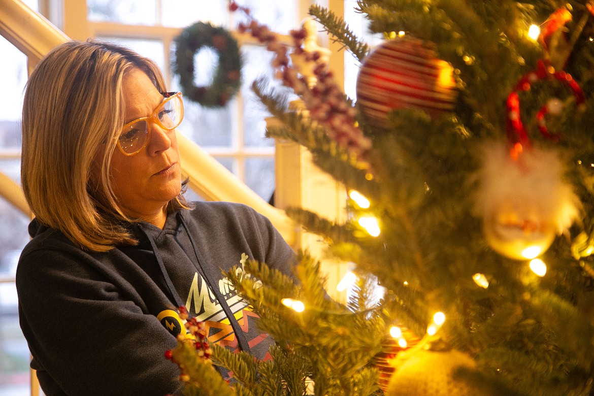 Kari Palmer decorates a Christmas tree at McDuff's Brewing Company on Friday. Over 20 trees will go up for bid as a part of Kinderhaven's annual fundraiser.