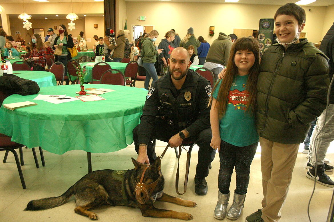 Moses Lake Police Department K-9 Officer Nick Stewart, left, and retired K-9 Chief pose for a picture with Tempi Whisler, center, and Ben Goebel during the Cocoa for K9s fundraiser Saturday at the Elks Lodge in Moses Lake.
