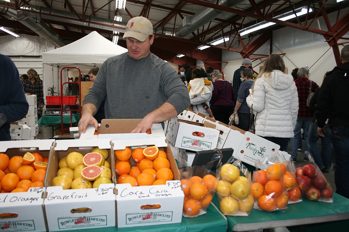 Mark Rowley of Rowley & Hawkins Fruit Farms adds to the displays at his stand during the Moses Lake Farmers Market Winter Market Saturday at the Grant County Fairgrounds.