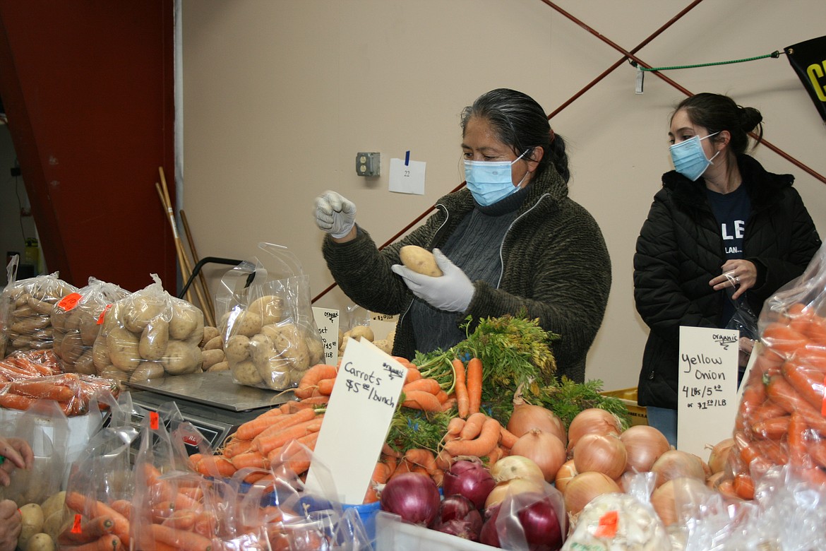Araceli Guadarrama, with Royal Produce, fills a bag for a customer during the Moses Lake Farmers Market Winter Market Saturday.