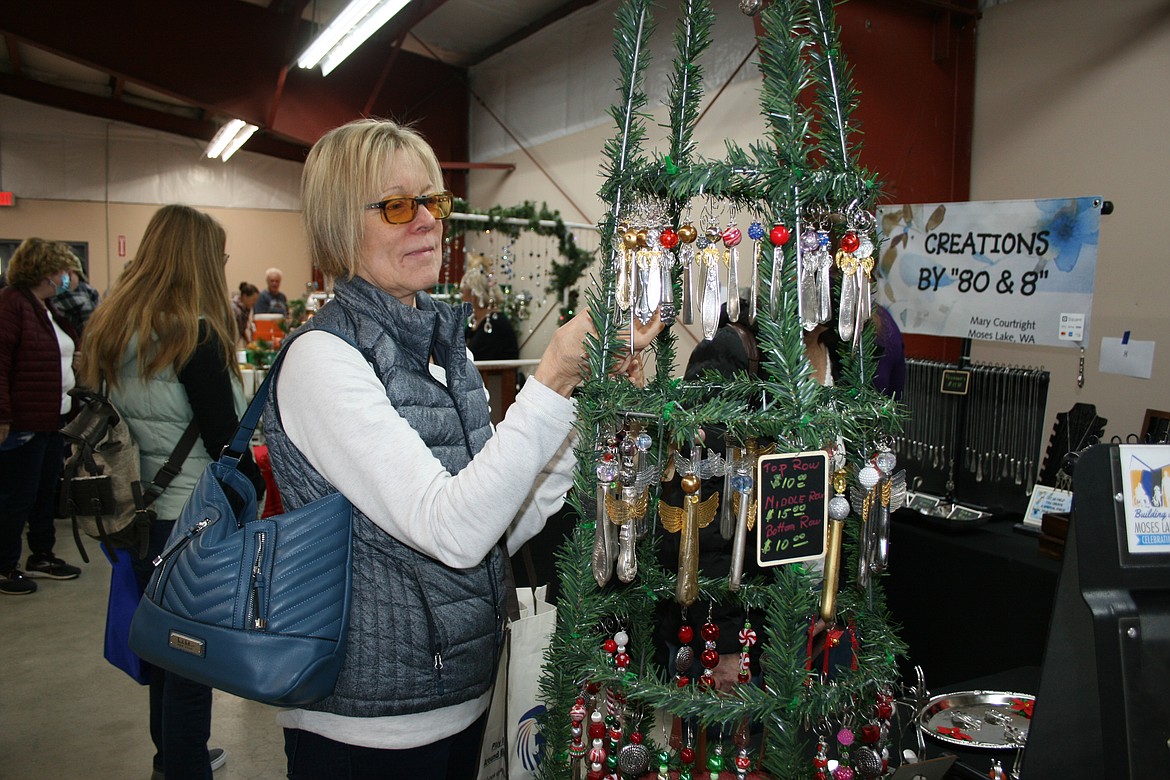 Sue Seibel looks through ornaments made from recycled silver during the Moses Lake Farmers Market Winter Market at the Grant County Fairgrounds Saturday.