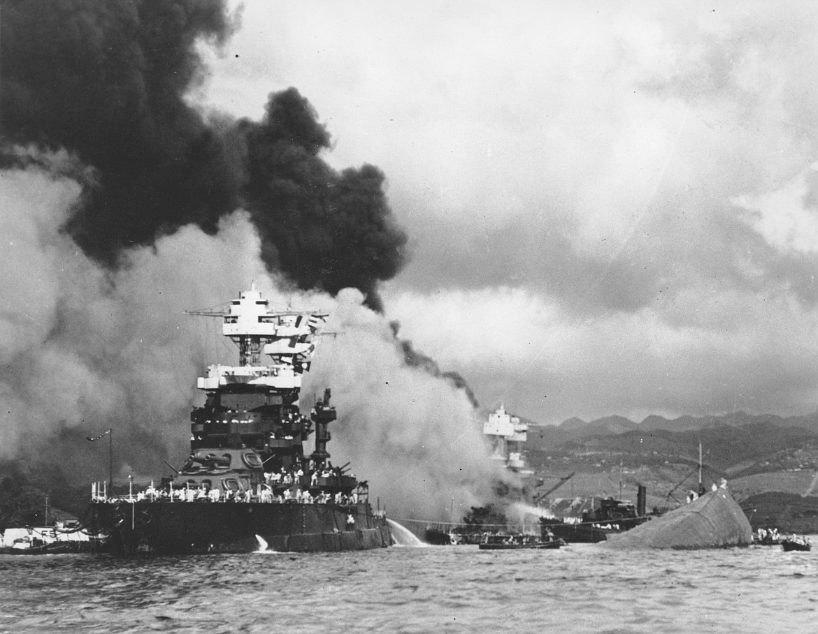 In this Dec. 7, 1941, file photo, part of the hull of the capsized USS Oklahoma is seen at right as the battleship USS West Virginia, center, begins to sink after suffering heavy damage, while the USS Maryland, left, is still afloat in Pearl Harbor, Oahu, Hawaii. Pearl Harbor survivors and World War II veterans are gathering in Hawaii this week to remember those killed in the Dec. 7, 1941 attack. (U.S. Navy via AP, File)