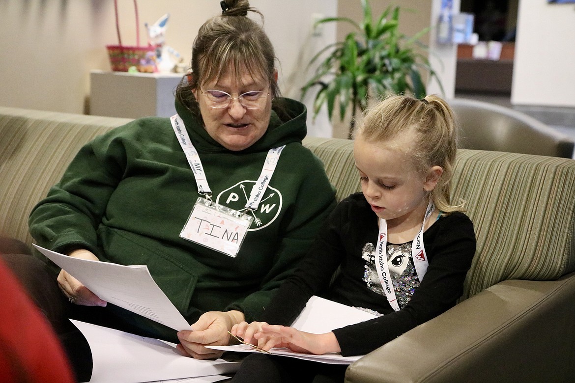 Six-year-old Aubriella Gibson sings Christmas carols while reading the lyrics in Braille, supervised by Tina Johnson, a teacher for the visually impaired, at North Idaho College on Saturday. The group of six visually impaired students practiced carols to perform at Evans Brothers Coffee Roasters in Coeur d'Alene. HANNAH NEFF/Press