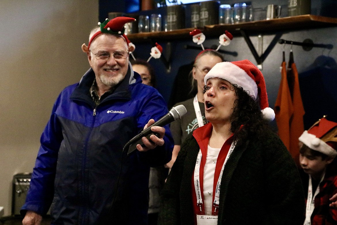 Gene Engebretsen holds the microphone for his wife Jordana, a teacher for the visually impaired, at her event for visually impaired students at Evans Brothers Coffee Roasters in Coeur d'Alene on Saturday. The students sang Christmas carols and handed out cards and gifts to audience in the coffee shop. HANNAH NEFF/Press