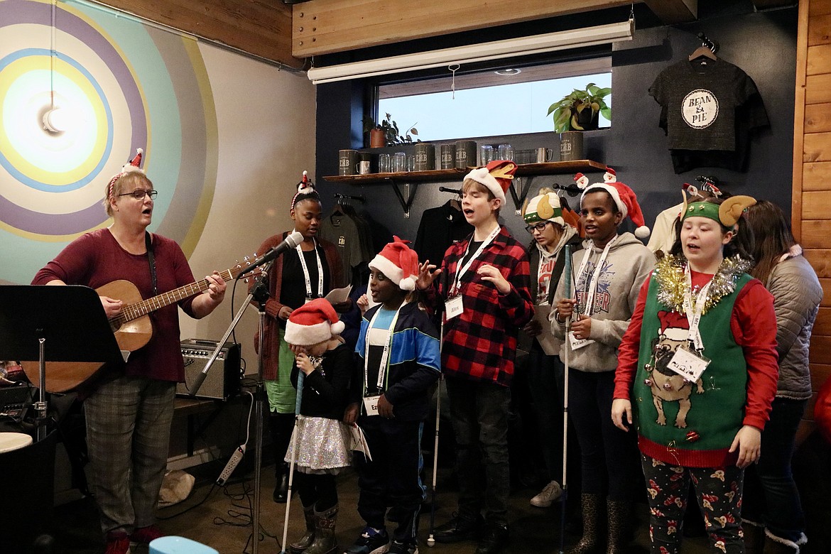 Carla Carnegie, on guitar, a teacher at Willow Song Music Therapy Services, leads visually impaired students singing Christmas carols at Evans Brothers Coffee Roasters in Coeur d'Alene on Saturday. HANNAH NEFF/Press