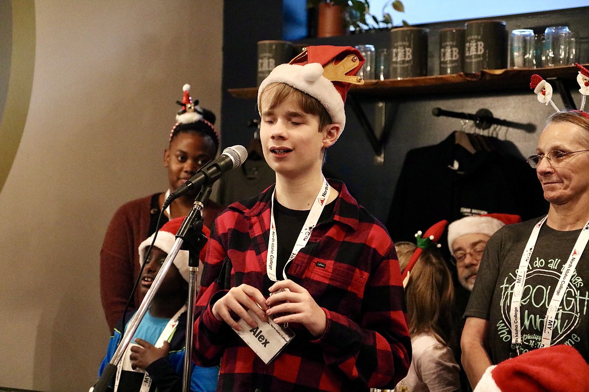 Thirteen-year-old Alex Owens, a visually impaired students, sings a Christmas solo for audience at Evans Brothers Coffee Roasters on Saturday. A group of six visually impaired students, assisted by volunteers, caroled and passed out Christmas cards and gifts to all in the coffee shop in Coeur d'Alene. HANNAH NEFF/Press