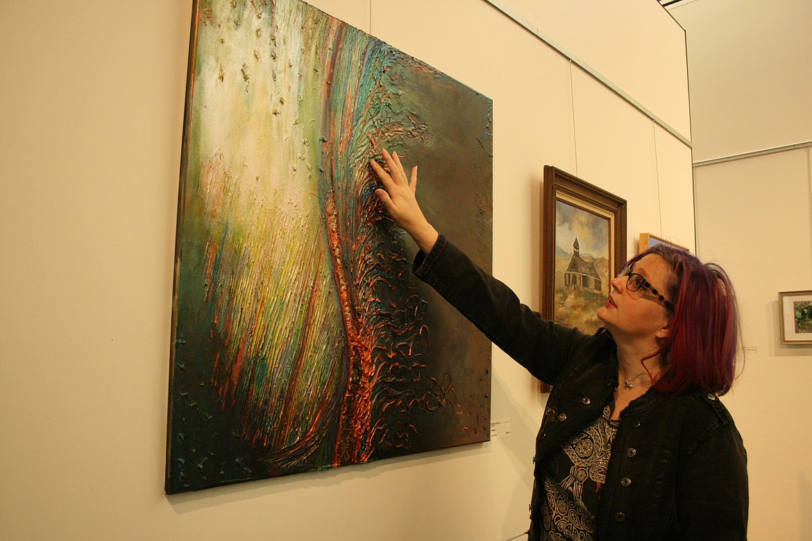 Rebekah Littlefield highlights the texture on one of her paintings in the members only exhibit at the Moses Lake Museum & Art Center.