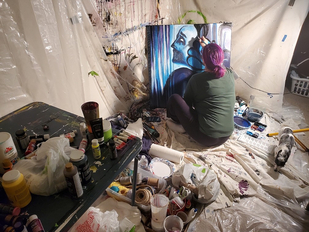 Rebekah Littlefield works on a painting in her home studio, with her dog Echo keeping her company.