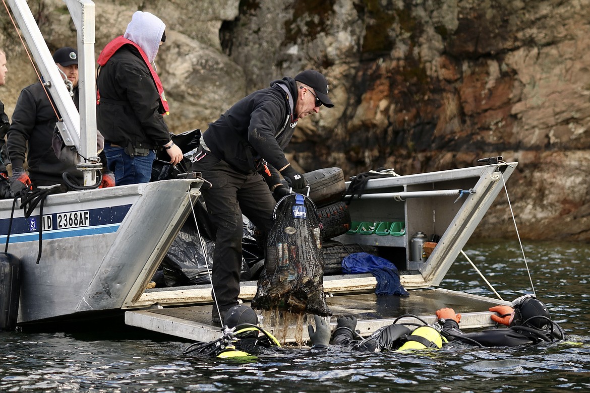 Doug Williams from Kootenai County Parks and Waterways Maintenance takes a bag from a KCSO dive team member during the underwater cleanup of Lake Coeur d'Alene Wednesday. HANNAH NEFF/Press