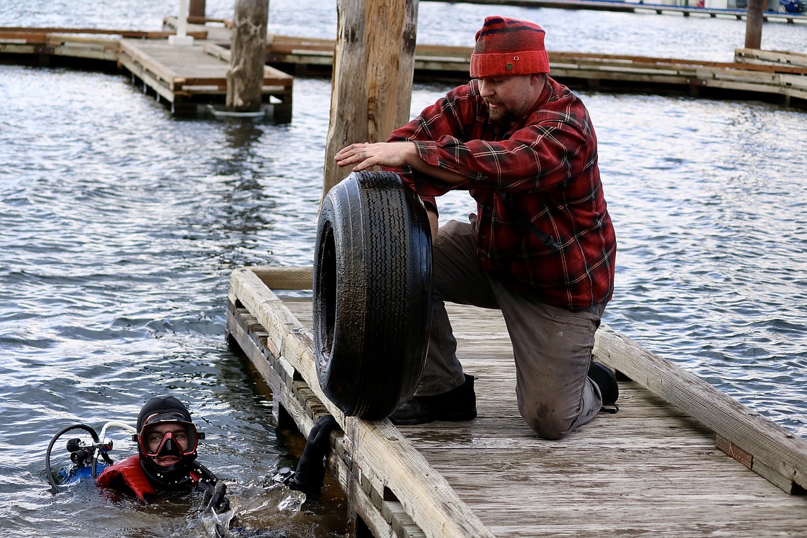 Volunteers Jasper Wilson of Post Falls collects a tire from 17-year-old Everett Hannah of Priest River during the underwater cleanup of Lake Coeur d'Alene near Tubbs Hill and the Third Street boat launch on Wednesday. HANNAH NEFF/Press