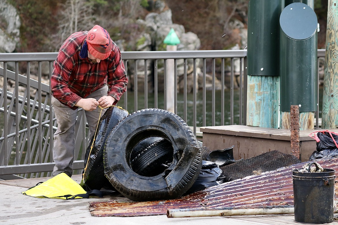 Volunteer Jasper Wilson of Post Falls ties together some of the around 100 tires pulled out of Lake Coeur d'Alene during the underwater cleanup on Wednesday. HANNAH NEFF/Press
