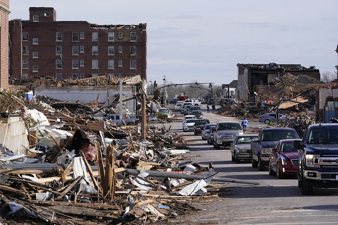 People survey damage from a tornado is seen in Mayfield, Ky., on Saturday, Dec. 11, 2021. Tornadoes and severe weather caused catastrophic damage across multiple states late Friday, killing several people overnight. (AP Photo/Mark Humphrey)