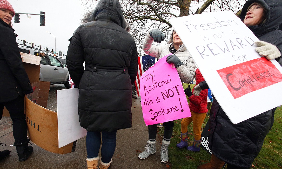 People hold signs at U.S. 95 and Ironwood Drive on Saturday outside Kootenai Health.