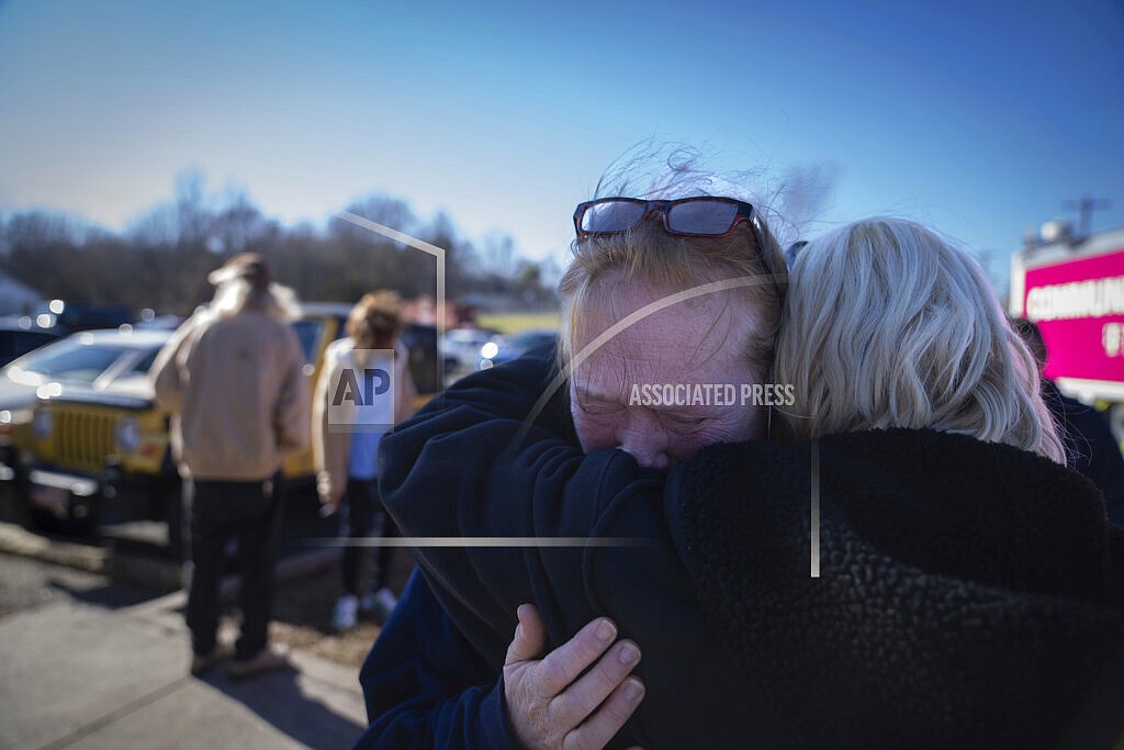 Tamara Yekinni hugs a friend outside a shelter in Wingo, Ky., on Sunday, Dec. 12, 2021, after residents were displaced by a tornado that caused severe damage in the area. Yekinni is an employee at a candle factory where employees were killed and injured by the storm. (AP Photo/Robert Bumsted)
