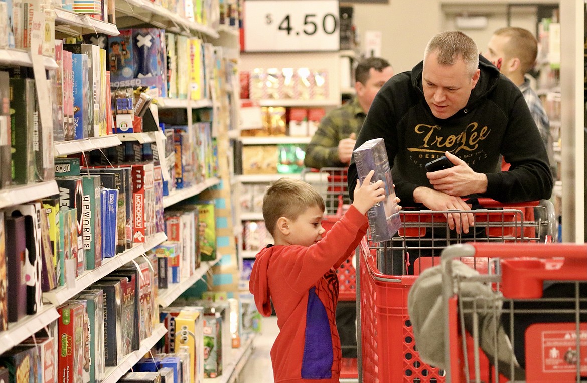 Five-year-old Logan places a Christmas gift for a family member in the shopping cart, pushed by his shopping buddy First Sergeant Will Knapp. Local children of deployed soldiers got to play Santa with the assistance of local military members on Tuesday morning at Target in Coeur d'Alene. HANNAH NEFF/Press