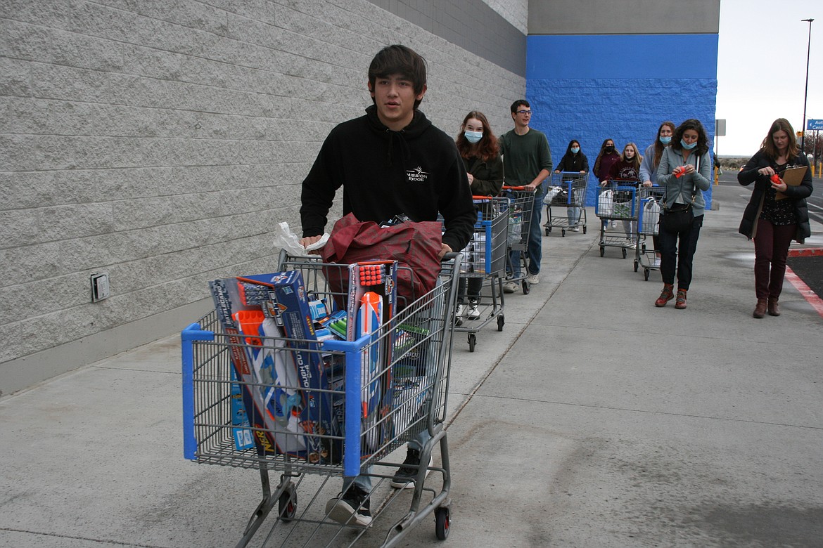 Santino McDonnell leads the parade of shopping carts back to the bus after buying gifts for the Toys for Teens project at Ephrata High School Monday.