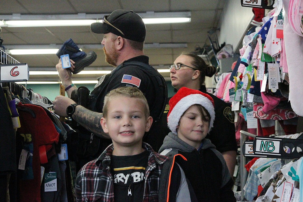 Odin Gentry, 8, left, and Braxton Graves, 10, shop for boots with Libby Police officer Chris Pape and Beckie Guerra, Lincoln County Sheriff's Office detention center officer, at Styches Consignment & Thrift as part of Shop with a Cop.