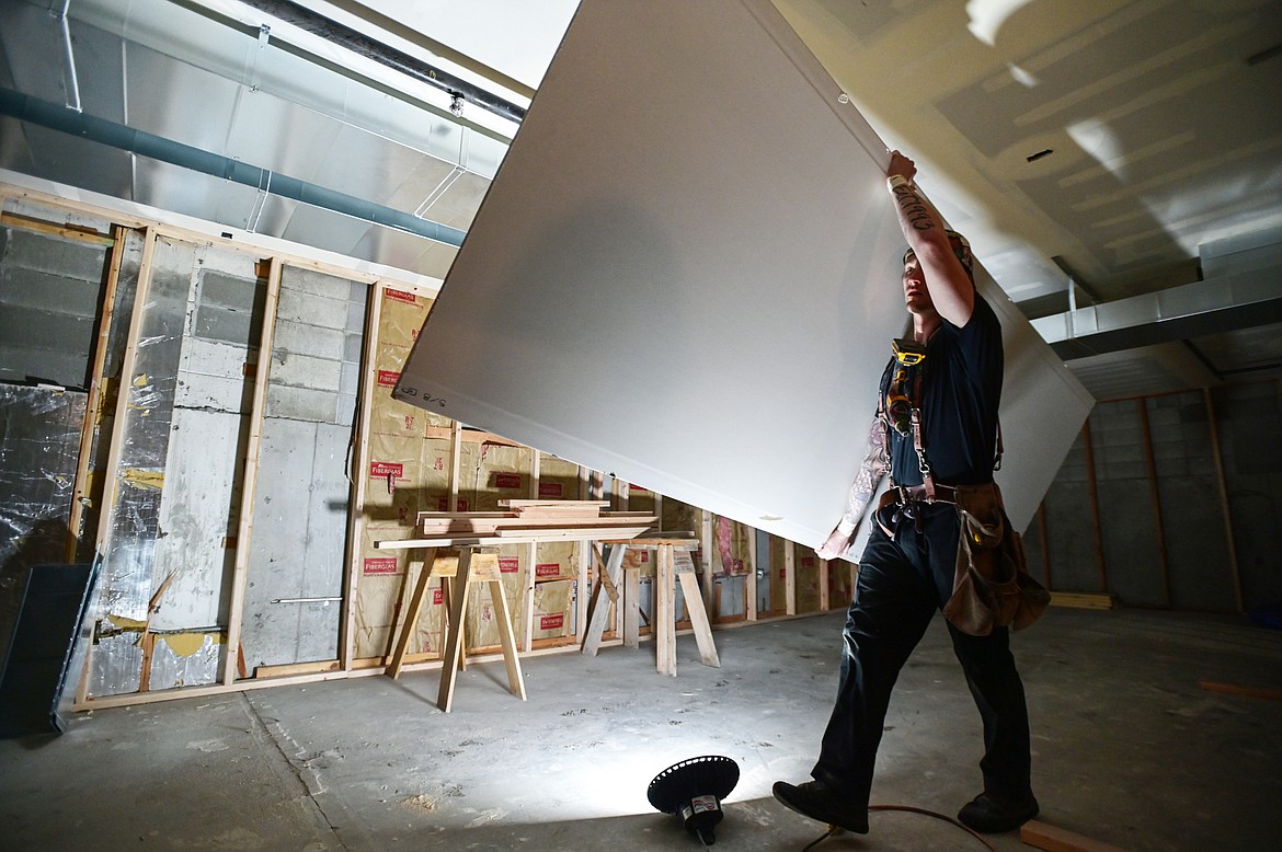 Jacob Tudahl, with RDJ Brothers, carries a  panel of sheetrock to install inside the county's North Campus Building in Kalispell on Thursday, Dec. 16. (Casey Kreider/Daily Inter Lake)