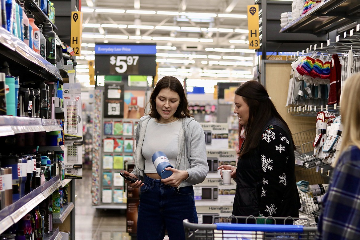 Lake City High School senior Lexi Doyle, left, selects and item to purchase for families in need while teacher Kelli Plaster watches at the Walmart in Hayden on Wednesday morning. The students in LCHS teacher Matt Ruchti's economics class raised over $7,000 to purchase food and gifts for individuals and families through Family Promise and the Union Gospel Mission in Coeur d'Alene. HANNAH NEFF/Press