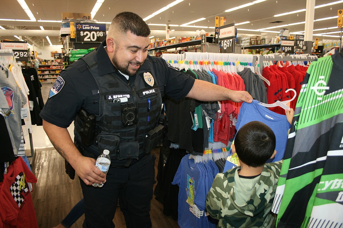 Moses Lake Police Department Detective Juan Serrato (left) and Benito Gutierrez look for the perfect superhero shirt during Shop With A Cop Tuesday in Moses Lake.