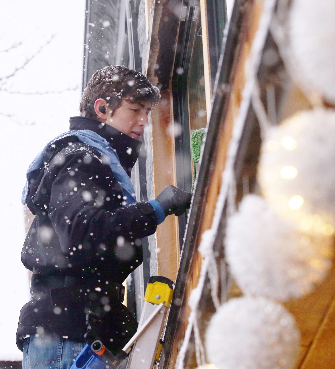 Edward Clark of Mountain Water Window Cleaning stands on a ladder as he goes over the window of a Sherman Avenue business during Thursday's snowstorm.