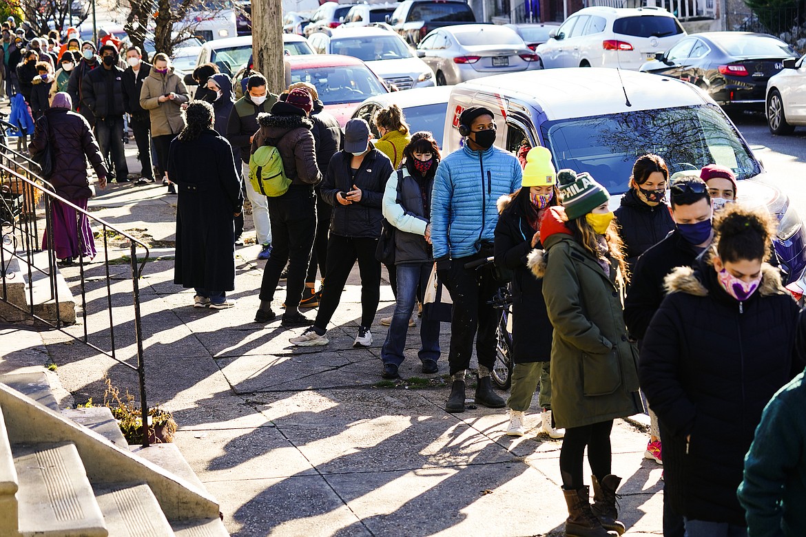 City residents wait in a line extending around the block to receive free at-home rapid COVID-19 test kits in Philadelphia, Monday, Dec. 20, 2021. (AP Photo/Matt Rourke)