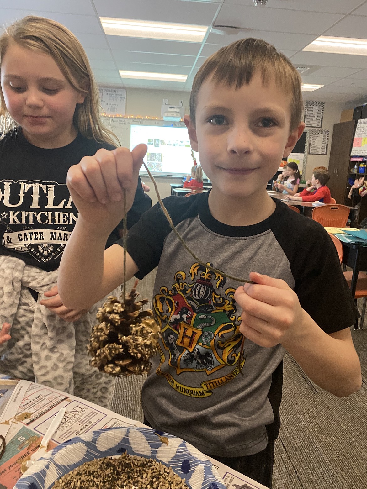 Fellow bird-lovers Annabella Hoye, 9, and Jacob Fritz, 8, enthusiastically slather sunflower butter and copious quantities of bird-seed on their bird-feeder ornaments Friday at Treaty Rock Elementary School.