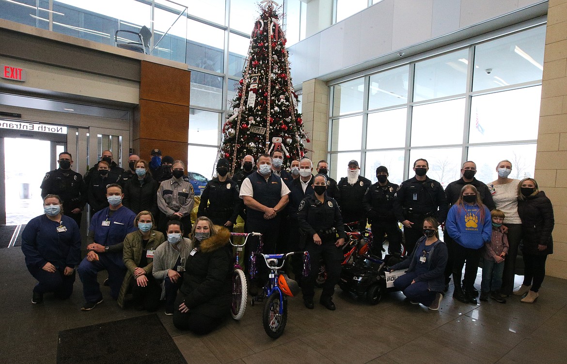 Monday was a happy day at Kootenai Health as Les Schwab employees and Coeur d'Alene Police personnel tuck presents under the tree for young patients.