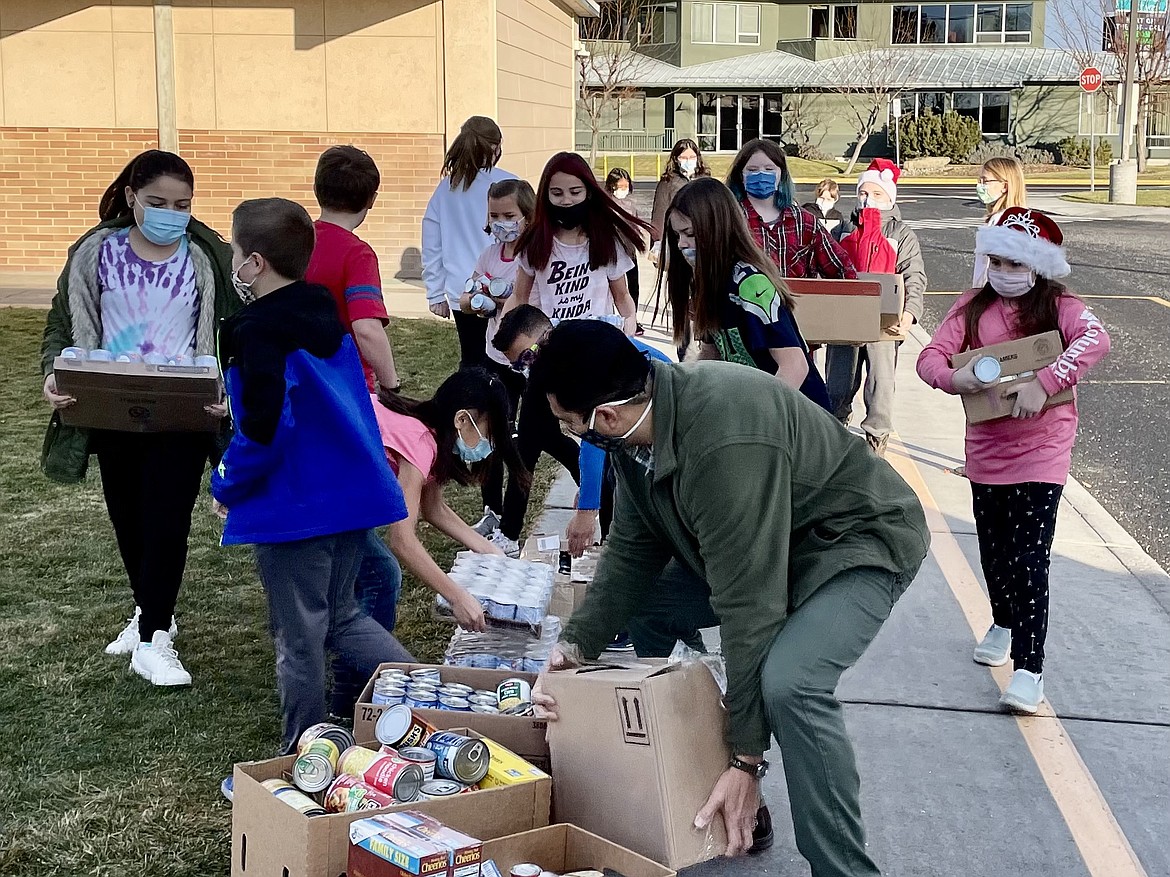 Garden Heights Elementary School teacher Will Caballero (center front, in green jacket) and his fourth-grade students carry their food donations to the waiting Moses Lake Food Bank truck.