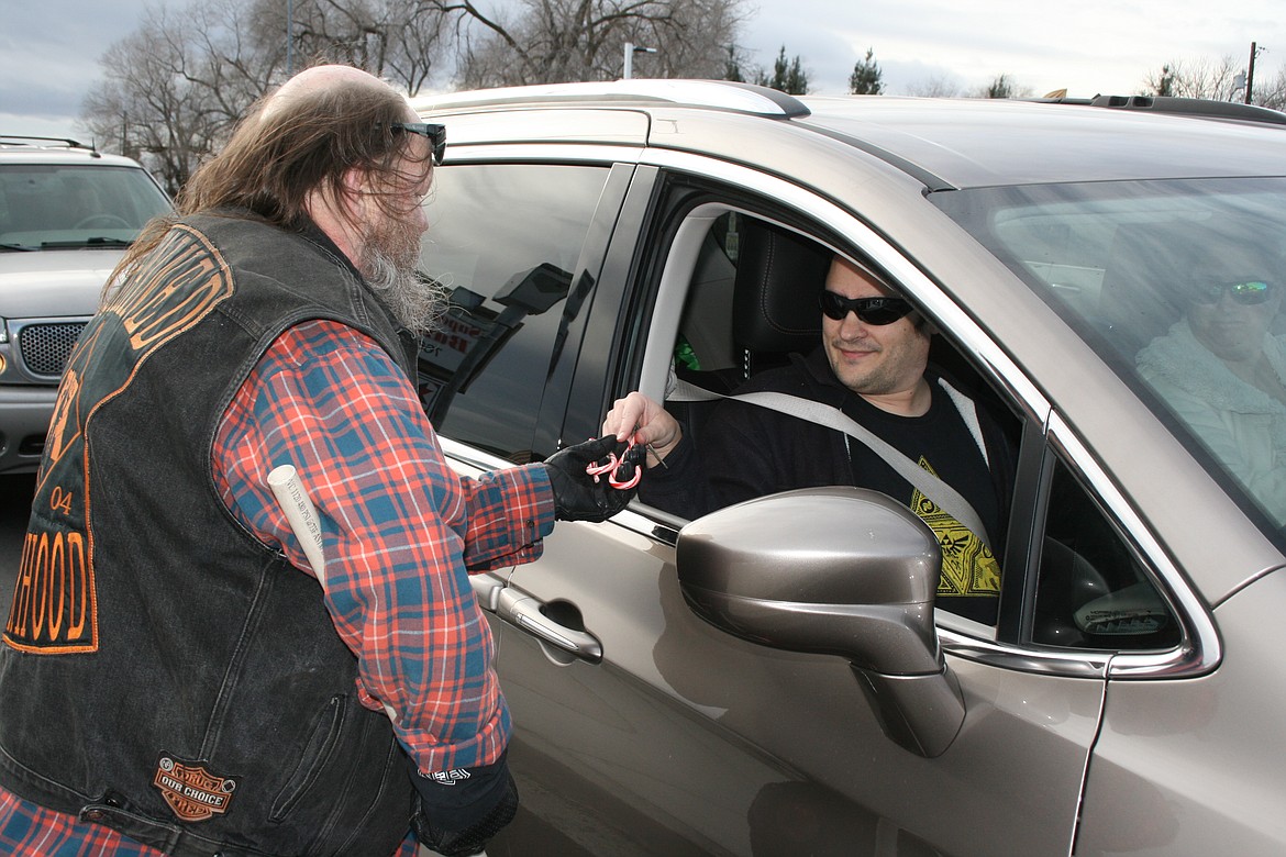 Jack Watrous (Papa Jack), founder of the Unchained Brotherhood MC, gives a candy cane to a passenger during the club’s fundraiser for the Moses Lake Food Bank toy distribution Dec. 11.