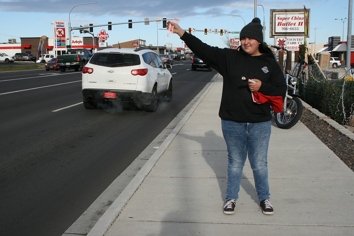 Lorraine Holland, daughter of Unchained Brotherhood MC member Ed Holland, waves to passers-by during the club’s fundraiser Dec. 11 for the Moses Lake Food Bank toy distribution.