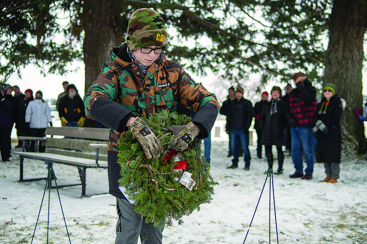 Jakob Underdahl places a wreath to commemorate Army soldiers lost at war during the Wreaths Across America ceremony at the Montana Veterans Home cemetery in Columbia Falls Saturday. Thousands of wreaths were placed on veteran graves in the Flathead Valley. (Chris Peterson/Hungry Horse News)