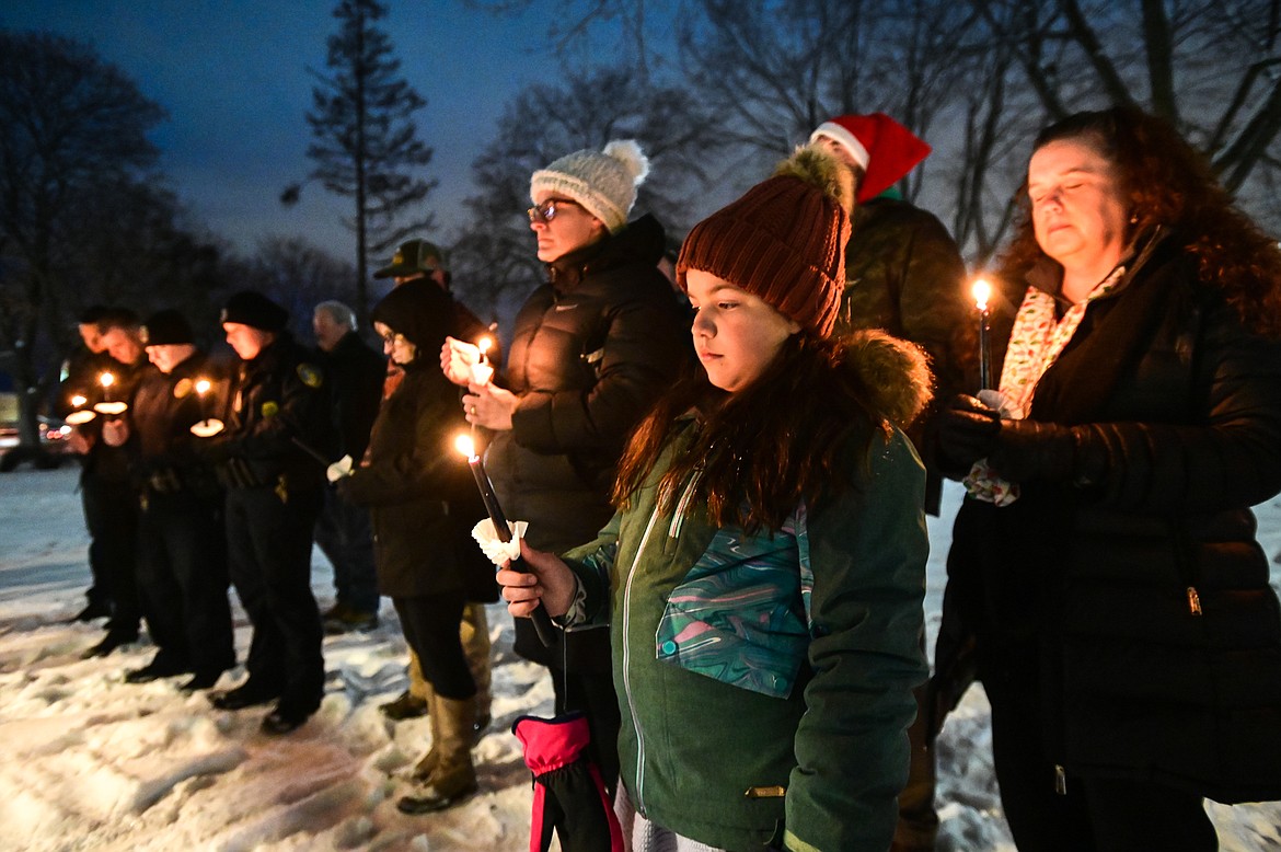 Finley Kipp and other attendees hold candles during a moment of silence at the Homeless Persons' Memorial Service at Depot Park in Kalispell on Tuesday, Dec. 21. Hosted by the Flathead Warming Center, the service was in memory of those who have died due to a lack of housing. (Casey Kreider/Daily Inter Lake)