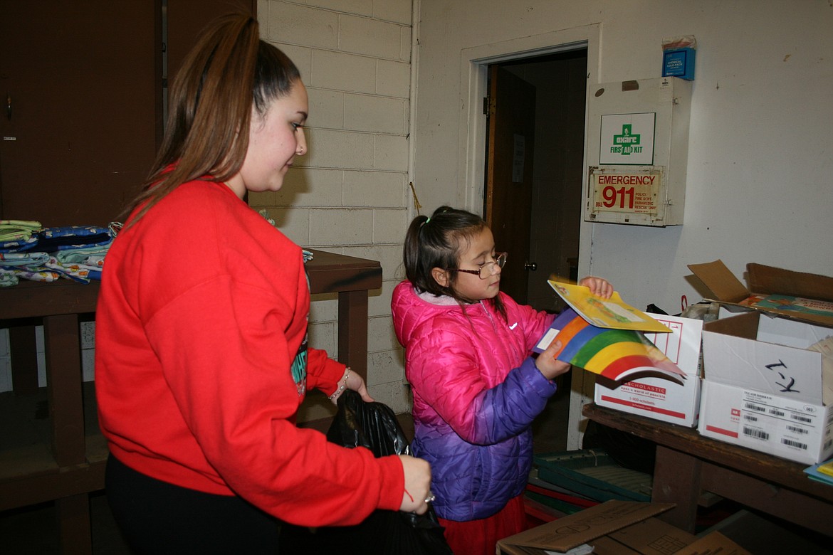 Mireya Alaya, left, and her sister Nayeli Alaya pick a book while bagging toys for the Othello Community Christmas Basket Program Thursday.