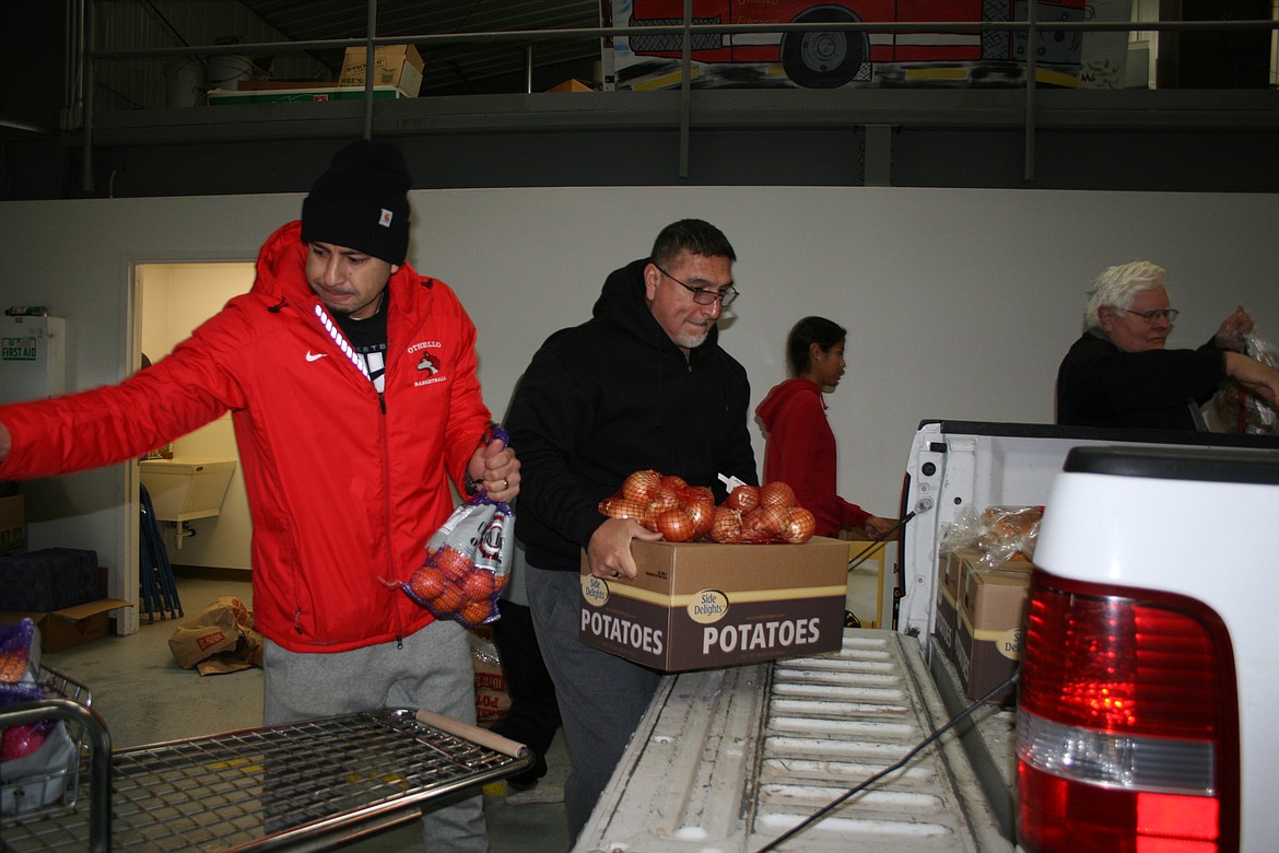 Othello girls basketball coaches Caleb Tovar, left, and Adolfo Coronado, right, load food for delivery during the Othello Community Christmas Basket Program Saturday.