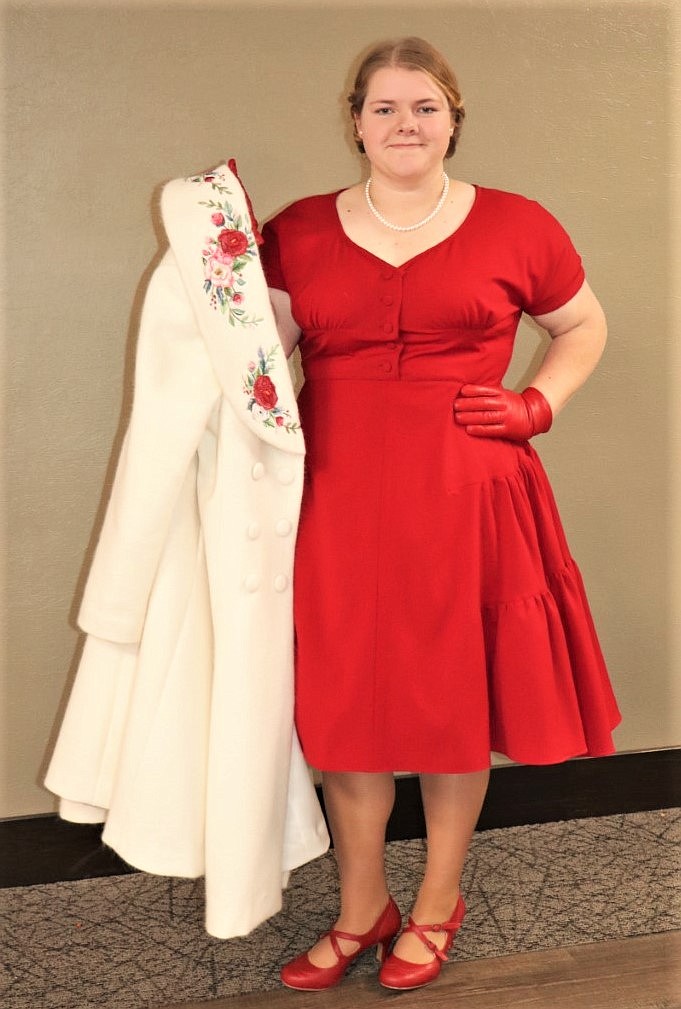 Kiara Sherman displays her double-breasted coat, featuring a floral rose waterfall embroidery along the shawl collar, and her rose red dress, fashioned from red wool and a vintage pattern. (Courtesy of Montana Make it With Wool)
