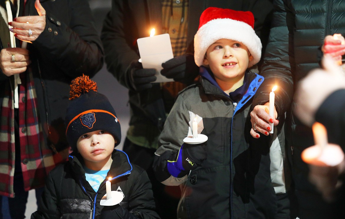 Abel Hall, right, and brother Easton Hall hold candles during Tuesday's vigil in Coeur d'Alene to honor the homeless.