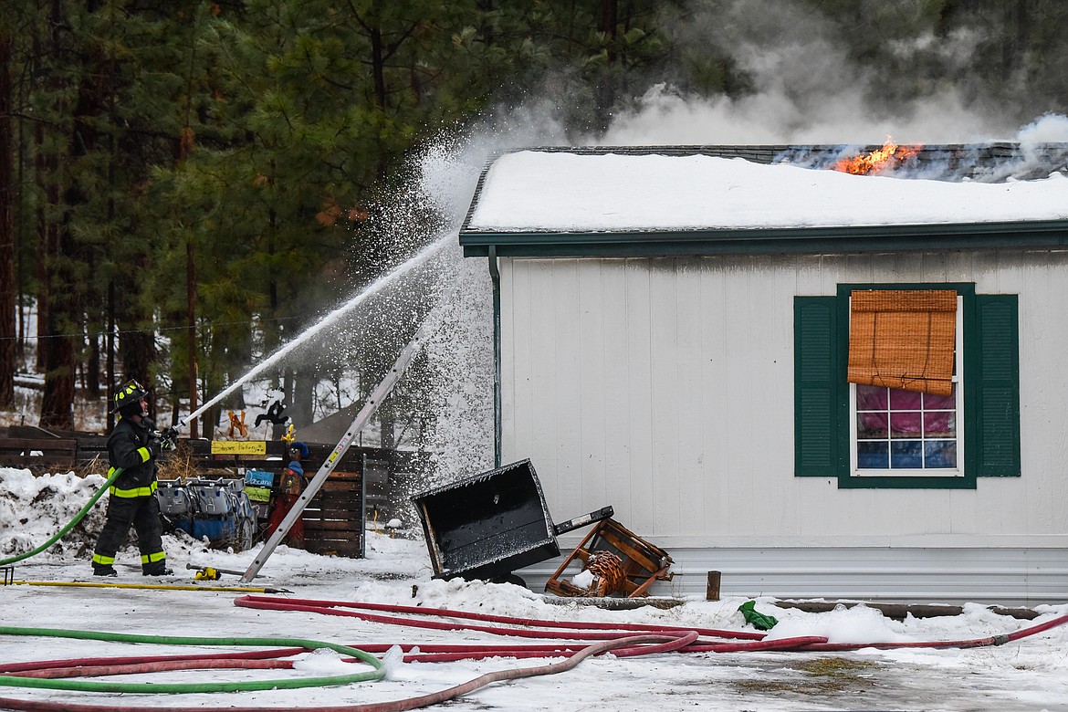 A firefighter battles a house fire along Tall Pine Ridge in West Valley on Thursday, Dec. 23. Fire crews from South Kalispell, West Valley and Smith Valley were on scene as well as the Flathead County Sheriff's and Flathead Electric. (Casey Kreider/Daily Inter Lake)