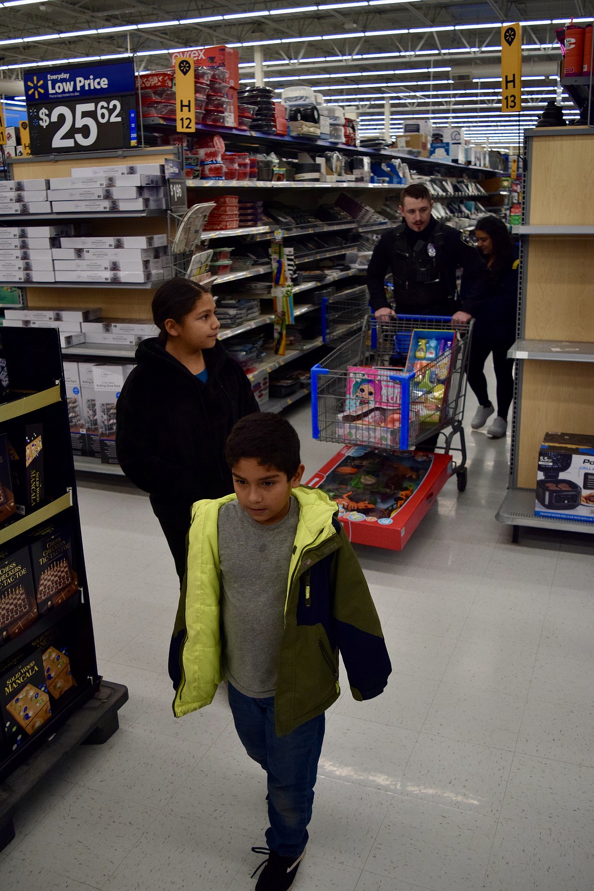 Zack Rodriguez, 6, front, walks an aisle in the Ephrata Walmart, while his sister Lidia Rodriguez, 9, his aunt Angelica Rodriguez and Soap Lake Police Department Officer Jeff Gallaher trail behind at the SLPD’s Shop With A Cop on Thursday.