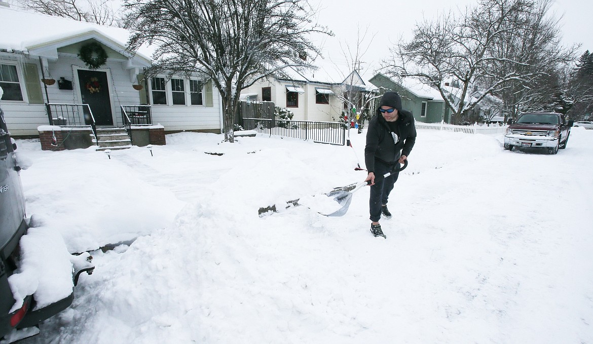 Downtown Coeur d'Alene resident Derek Zollinger shovels snow and chips ice from the road in front of his house Tuesday afternoon. Temperatures are expected to be as low as 20 below with the wind chill in the coming days.