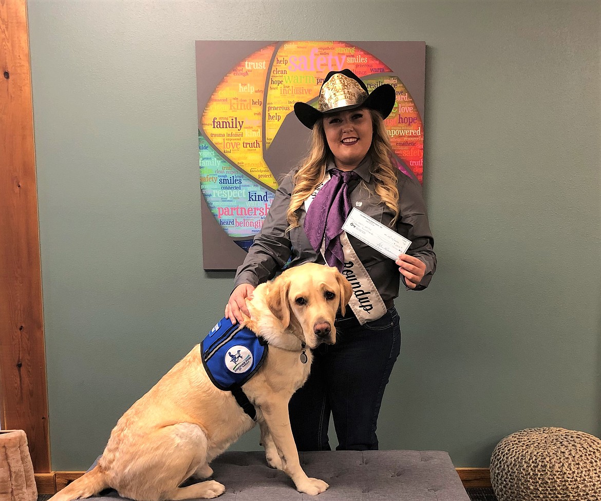 Mykiah Hollenbeck, 2020-21 Moses Lake Roundup queen, pictured with Kids Hope facility assistance dog Valor, presents a donation to the organization.