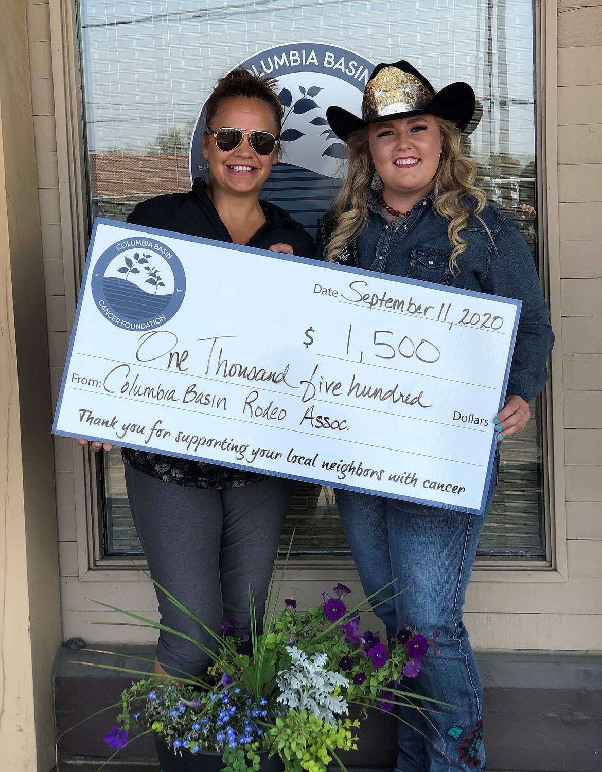 Angel Ledesma (left), director of the Columbia Basin Cancer Foundation, accepts a donation from the Columbia Basin Rodeo Association and 2020-21 Moses Lake Roundup queen Mykiah Hollenbeck.