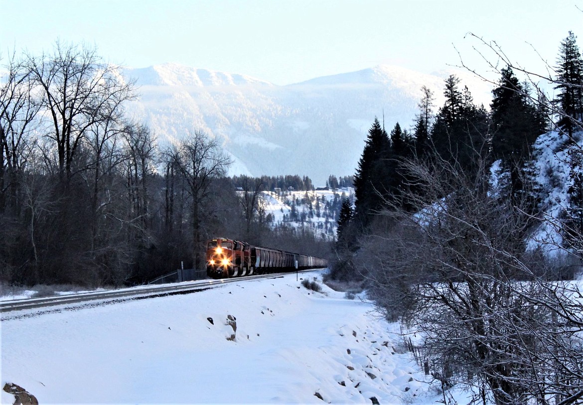 An early morning train drives through Cow Creek with the Percell Mountains in the background.