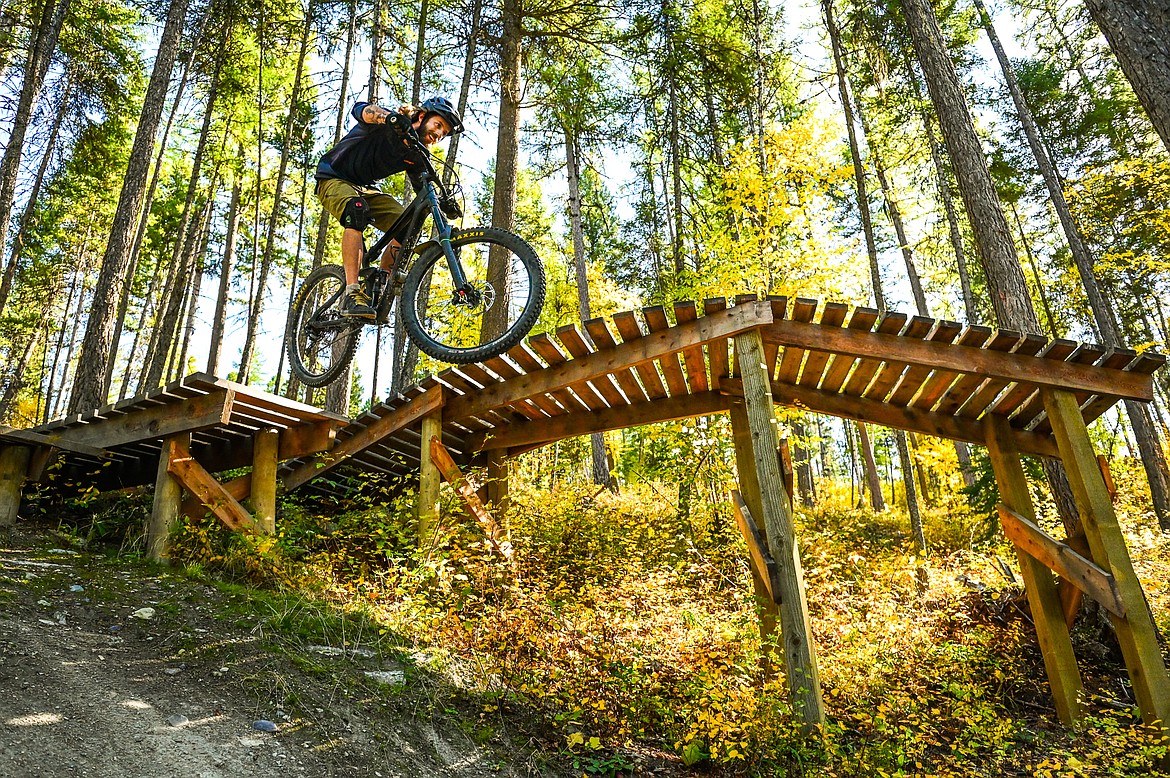 Greg Theis, Executive Director of Flathead Area Mountain Bikers, rides off a drop in the Malice in Plunderland trail near the North Spencer Mountain Trailhead in Whitefish on Thursday, Sept. 30. (Casey Kreider/Daily Inter Lake)