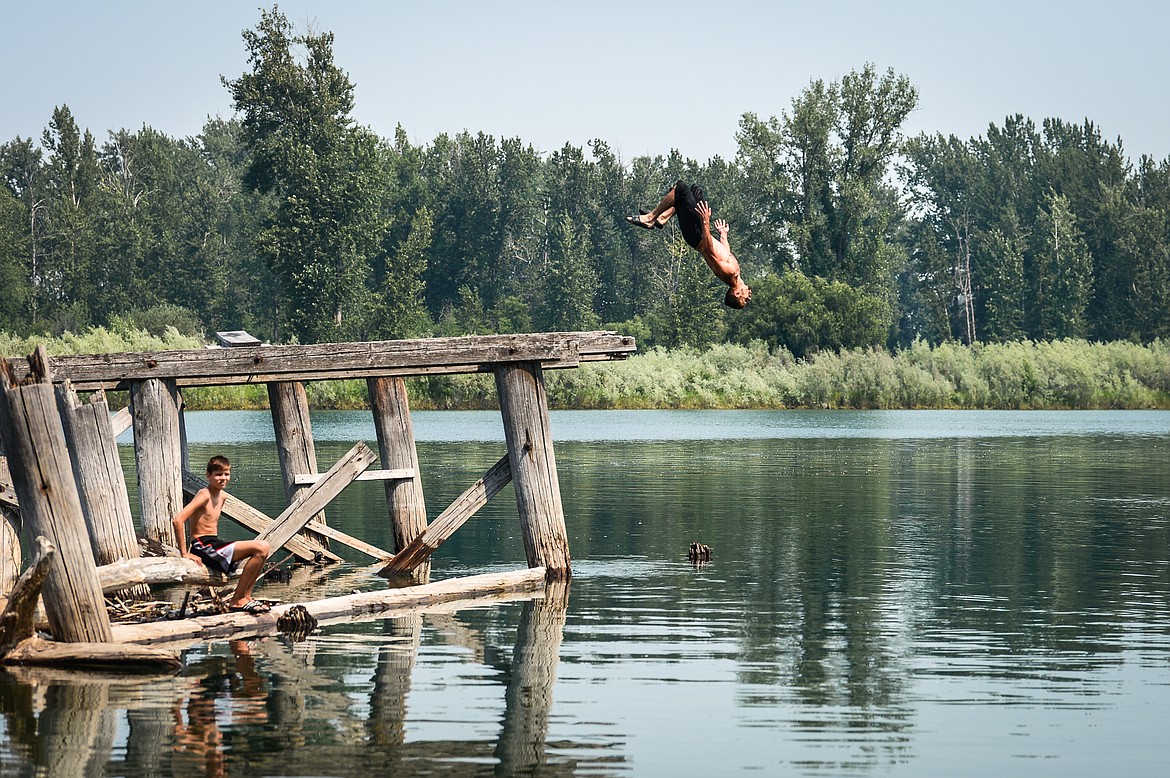 Vadim Khmelev, of Kalispell, backflips into the Flathead River as he and his brother Micah, bottom left, go for a swim on Thursday, July 15. (Casey Kreider/Daily Inter Lake)