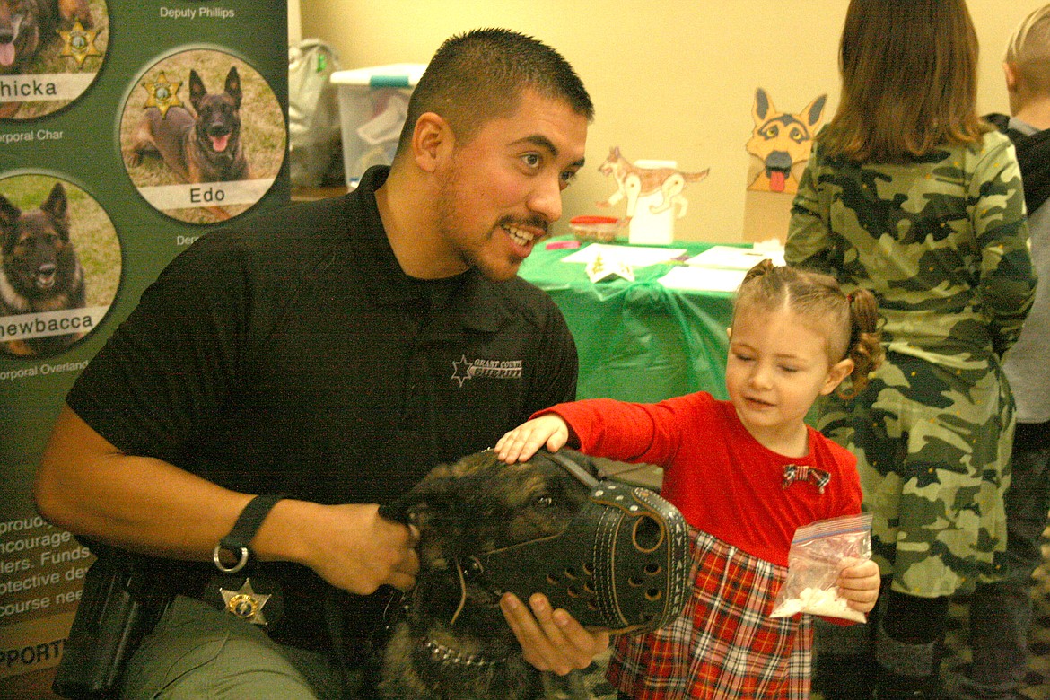 Grant County Sheriff’s Office Deputy Luis Jimenez (left) introduces K-9 Zedd to Byrnleigh-Rose Wixom during the Cocoa for K9s event at the Columbia Basin Elks Lodge Dec. 4.